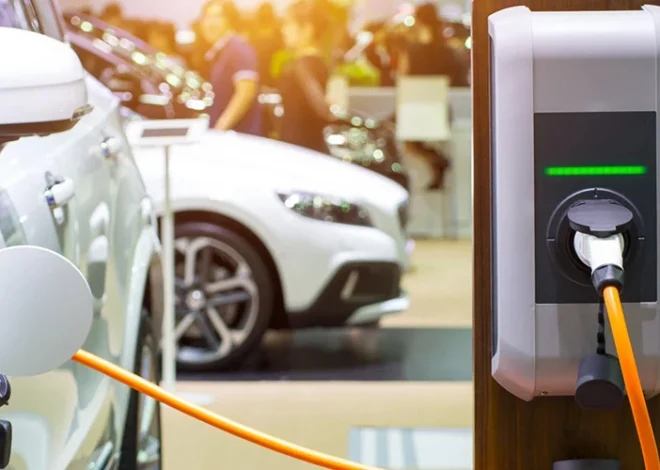 Electric car charging station plugged into a white car at a showroom or car expo.