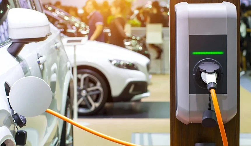 Electric car charging station plugged into a white car at a showroom or car expo.