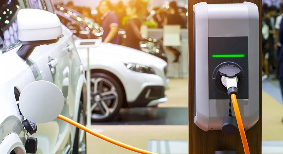 Electric car charging station plugged into a white car at a showroom or car expo.
