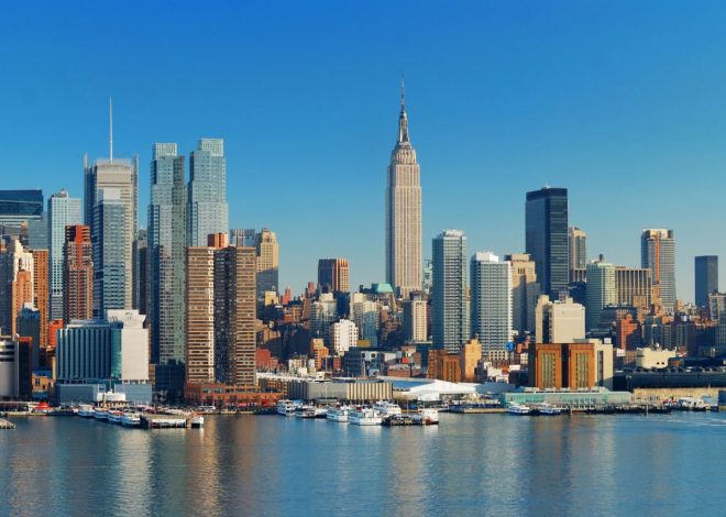 New York City skyline with the Empire State Building rising above the harbor and boats along the waterfront