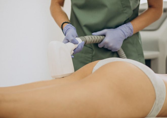 Gloved clinician performing a non-invasive body contouring treatment on a person lying face down over their buttocks with a handheld applicator.