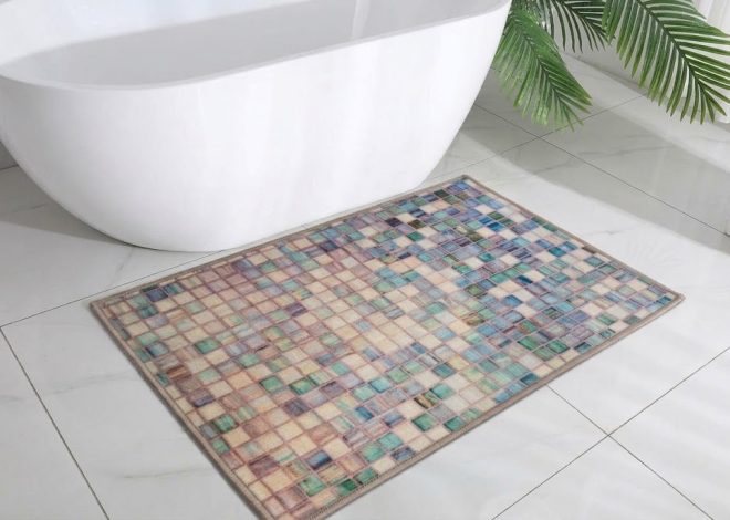 Multicolored mosaic rug on a white tiled bathroom floor beside a white freestanding tub and green plant leaves nearby.