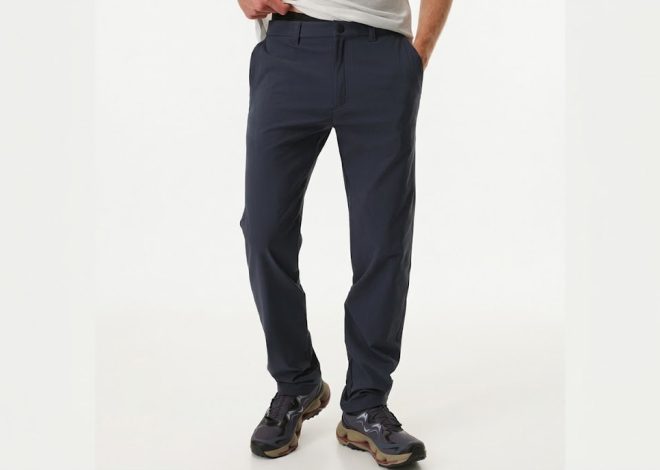 Person standing, wearing navy chinos or casual pants and dark hiking shoes, hands partially in pockets (front view).