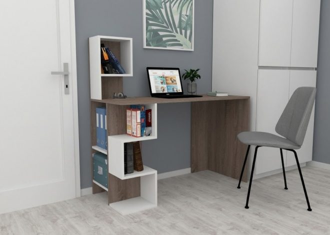 Home office desk with a laptop, chair, plant, and white shelving unit in a gray-walled room.