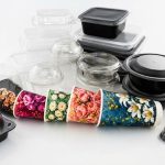 Assorted disposable food containers and floral-patterned paper cups arranged on a white surface.