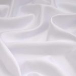 Close-up of soft white fabric with gentle folds and shadows.