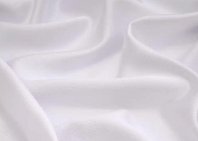 Close-up of soft white fabric with gentle folds and shadows.