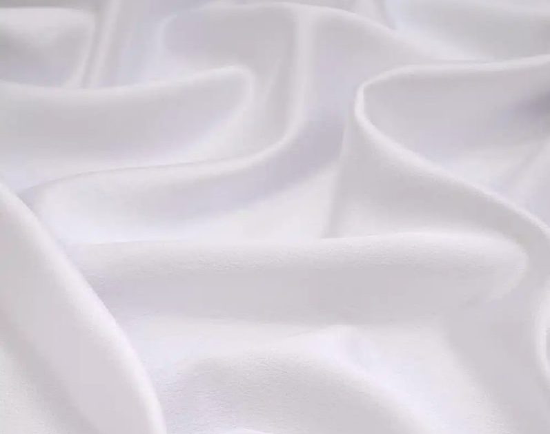 Close-up of soft white fabric with gentle folds and shadows.