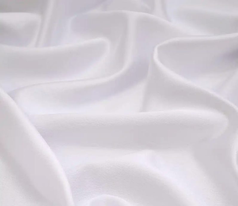 Close-up of soft white fabric with gentle folds and shadows.