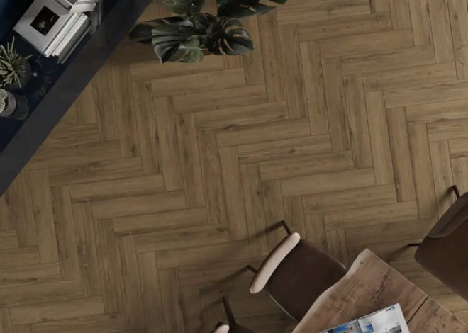 Overhead view of a herringbone wood floor with a small dining table and brown chairs, and potted plants in the corner.