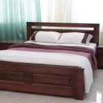 Queen-size wooden bed with matching nightstands, burgundy bedding and white pillows in a bright room with teal curtains.