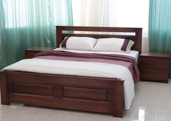 Queen-size wooden bed with matching nightstands, burgundy bedding and white pillows in a bright room with teal curtains.