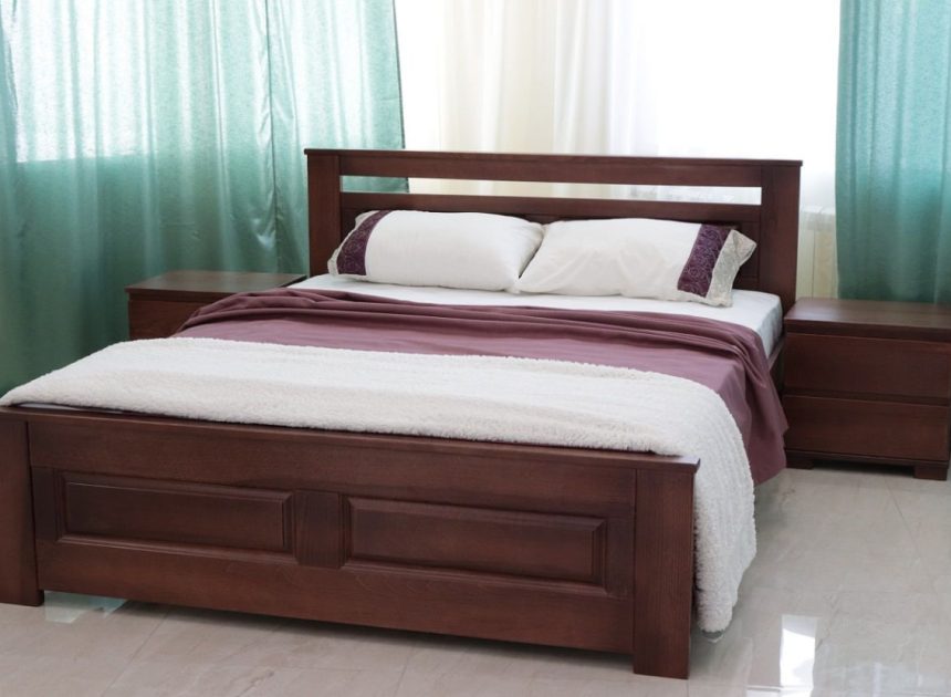 Queen-size wooden bed with matching nightstands, burgundy bedding and white pillows in a bright room with teal curtains.