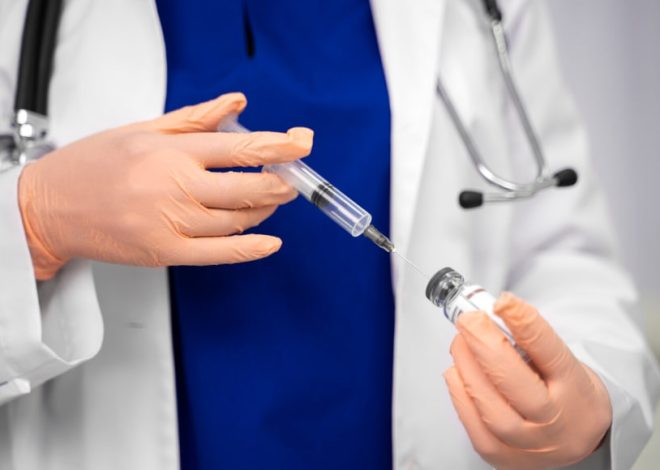 Doctor in gloves drawing vaccine from vial into a syringe in a clinical setting