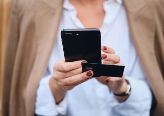 Person holding a smartphone and a credit card, ready to pay with a mobile wallet.