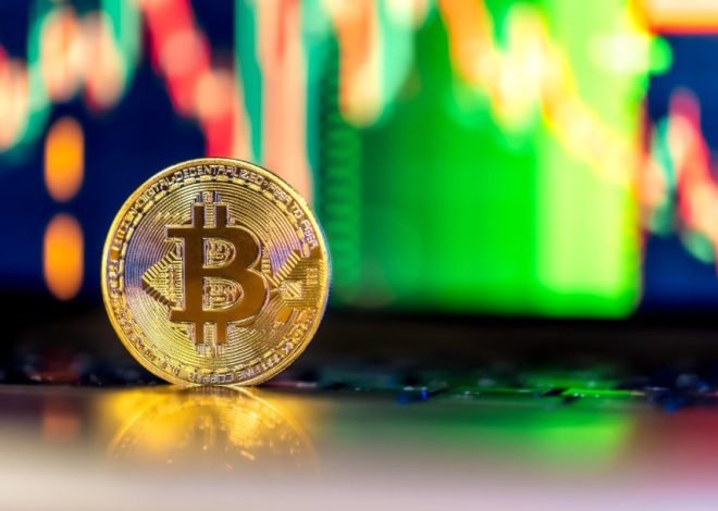 Bitcoin coin resting on a reflective surface with a blurred, colorful stock/crypto chart in the background, signaling cryptocurrency trading.