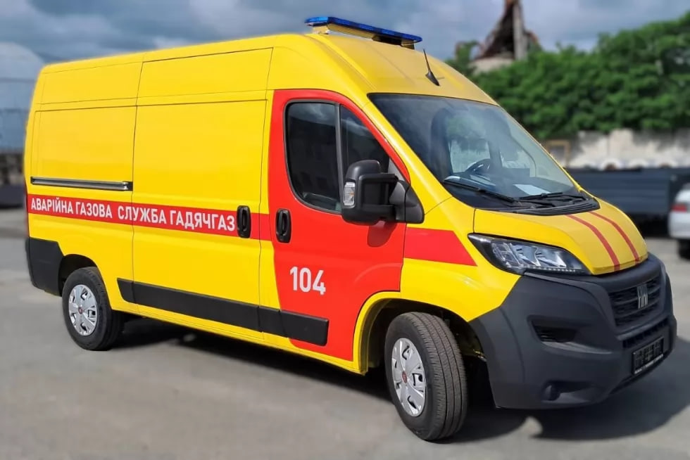 Yellow and red emergency van (ambulance) with '104' on the door and Cyrillic text along the side, ready for service.