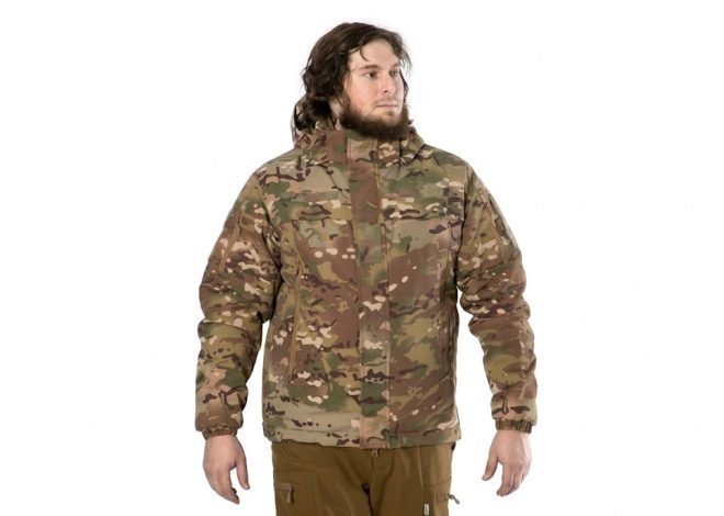 Man wearing a woodland camouflage jacket with a high collar, standing against a white background.