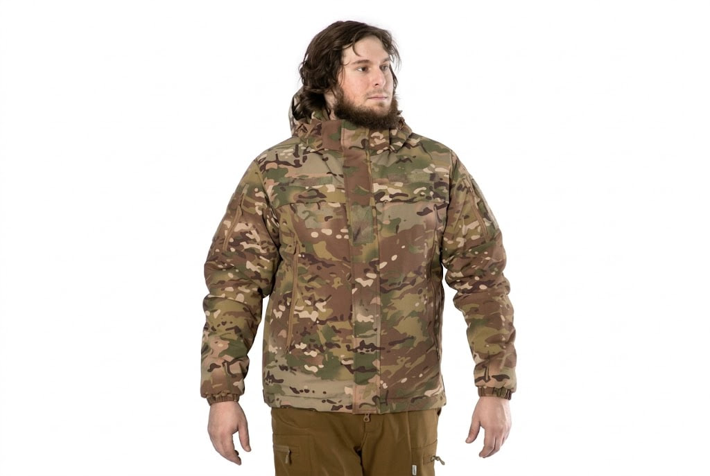 Man wearing a woodland camouflage jacket with a high collar, standing against a white background.
