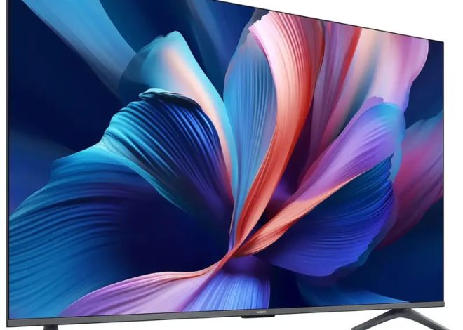 Flat-screen TV on a white background displaying a vibrant abstract wallpaper with blue and pink petals, thin bezel and angled stands.