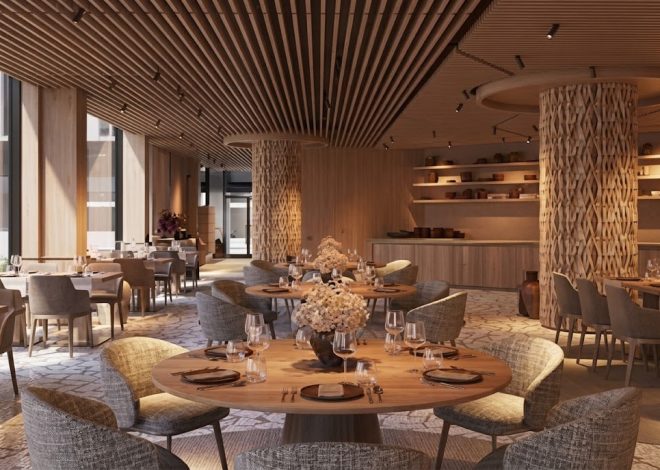 Elegant dining room with round wooden tables, gray upholstered chairs, and floral centerpieces in warm lighting
