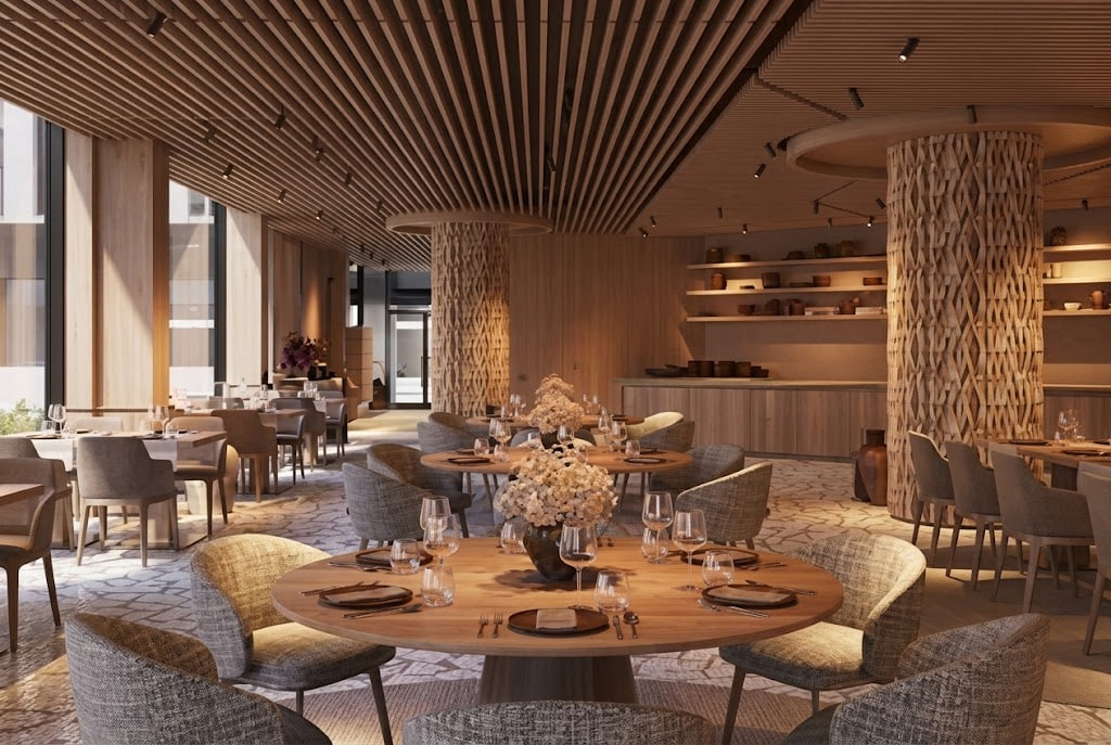Elegant dining room with round wooden tables, gray upholstered chairs, and floral centerpieces in warm lighting