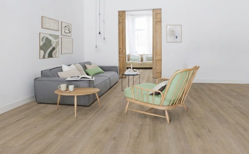 Cozy, minimalist living room with a gray sofa, green cushions, a round wooden coffee table, and a matching wood-framed chair in a bright space with art on the wall.